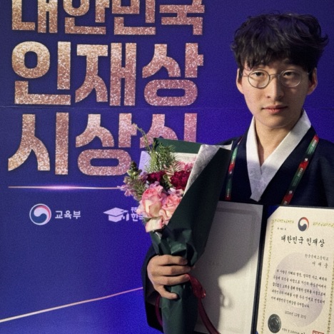 SuhJae wearing a navy-blue Hanbok (두루마기), holding the Korea Talented Award.